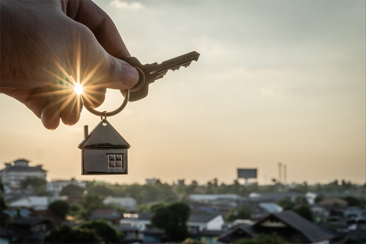 Hand holding house keys in the sunset